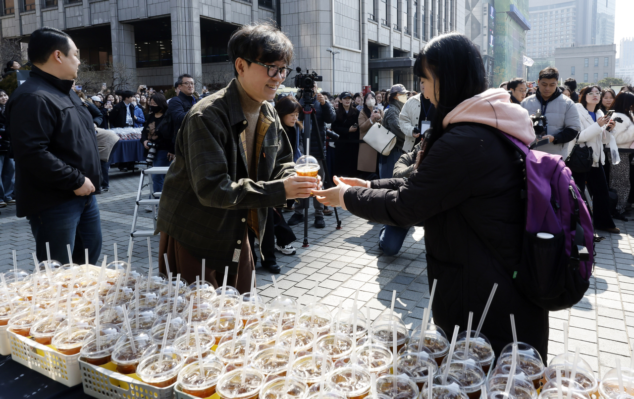 Director Jang Hang-jun hands a cup of coffee to a fan during a coffee truck event at the Korea Press Center in Seoul on Thursday. (Newsis)